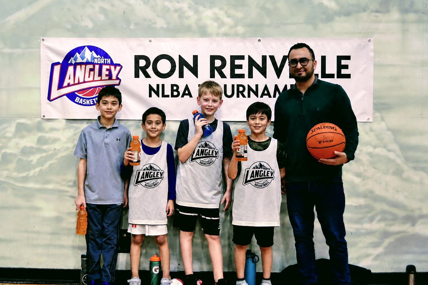 A young NLBA team with their coach holding a basketball at the tournament